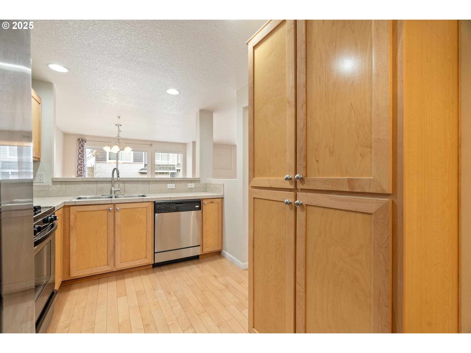 10723 Southwest Canterbury Lane, Unit 102 Portland, OR 97224 - Photo 12 of 30 a kitchen with kitchen island granite countertop wooden cabinets and white appliances