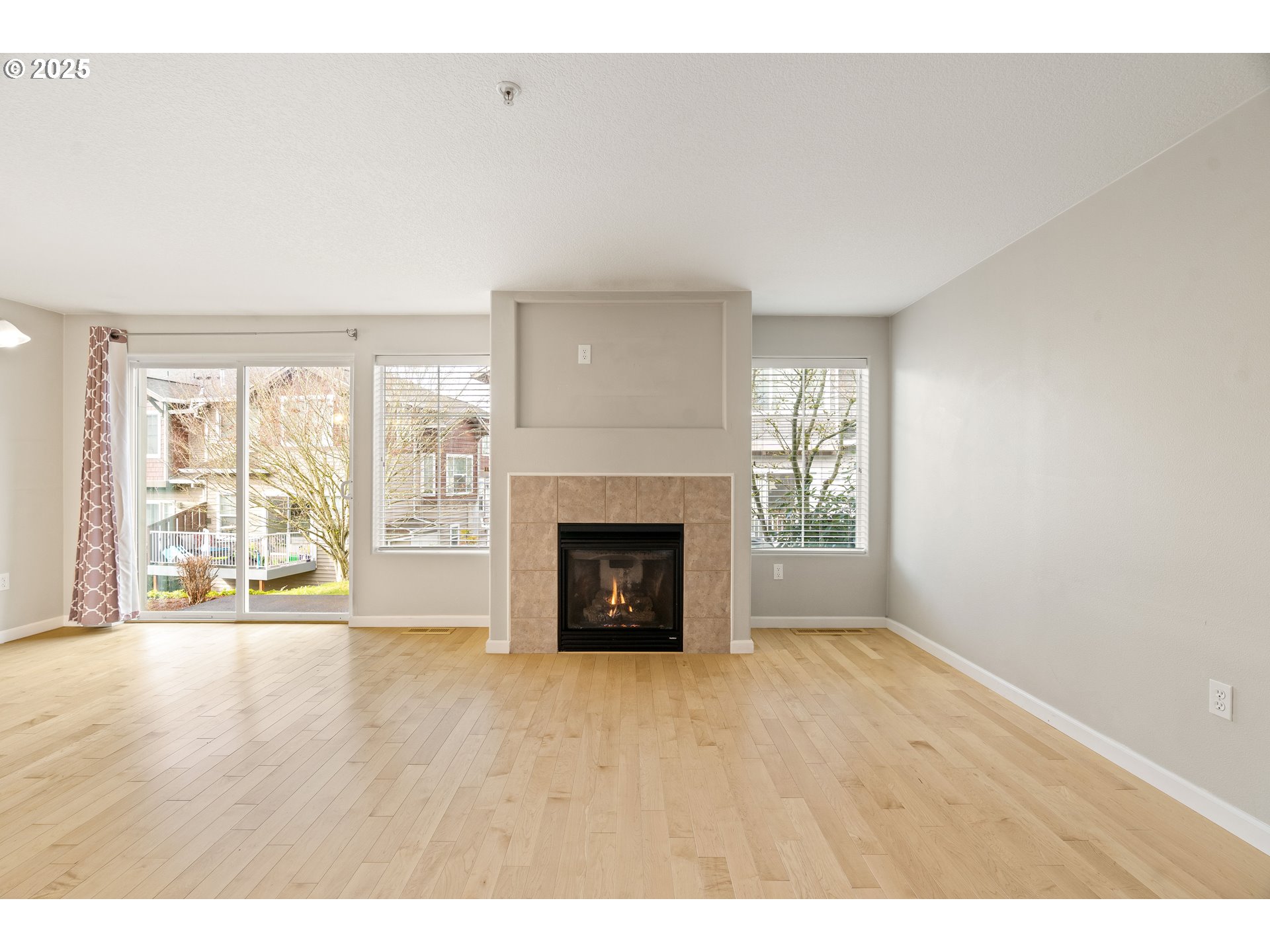 10723 Southwest Canterbury Lane, Unit 102 Portland, OR 97224 - Photo 17 of 30 a view of an empty room with a fireplace and a window