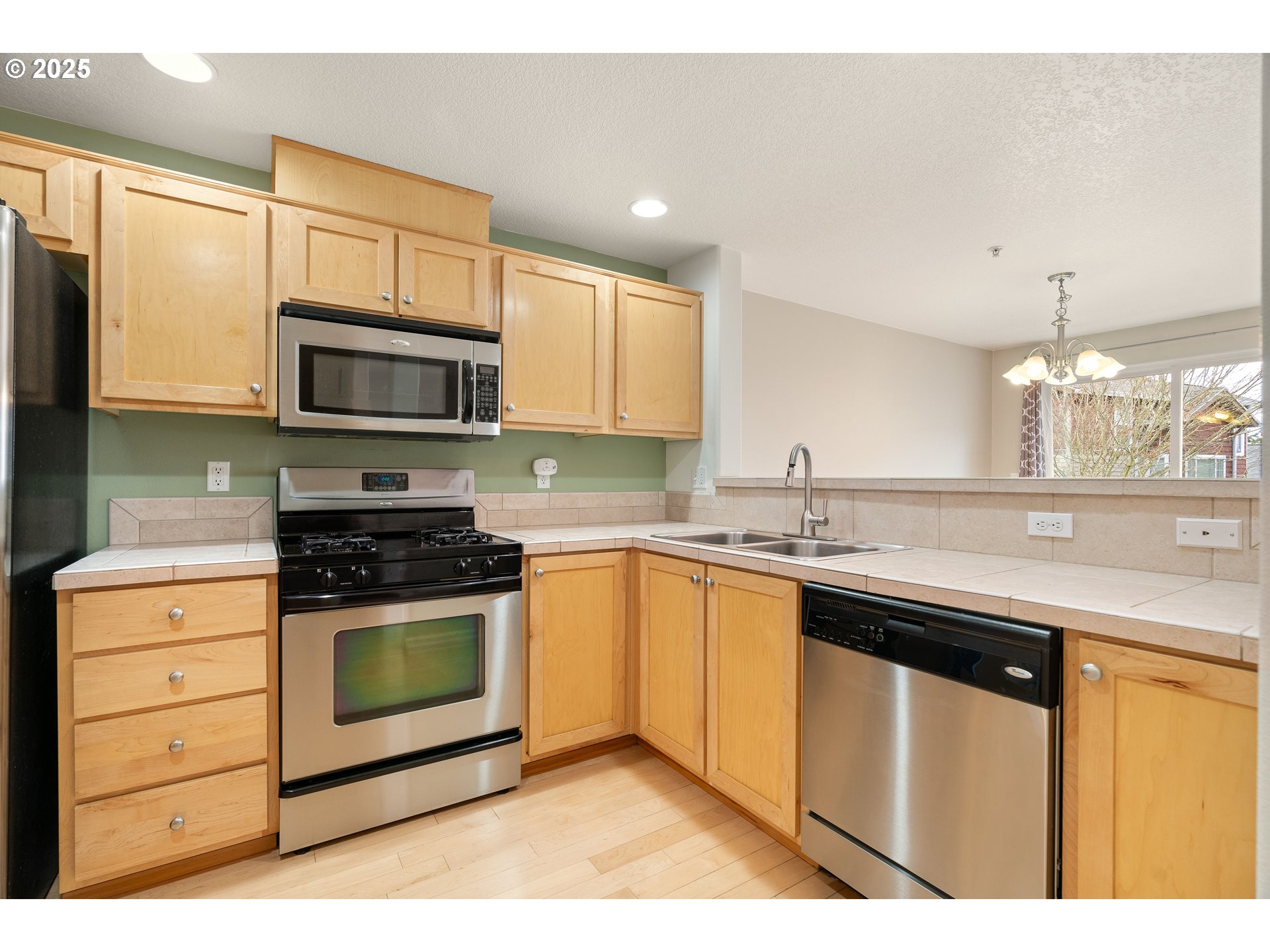 10723 Southwest Canterbury Lane, Unit 102 Portland, OR 97224 - Photo 9 of 30 a kitchen with stainless steel appliances granite countertop a sink stove and microwave