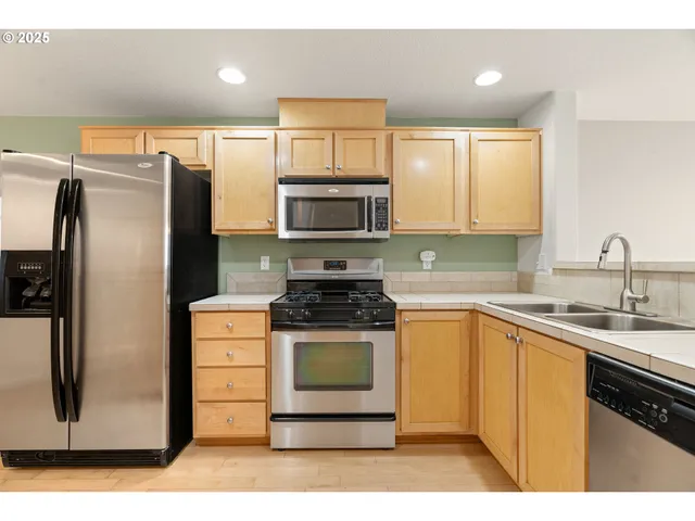 a kitchen with stainless steel appliances granite countertop a stove a sink and a microwave
