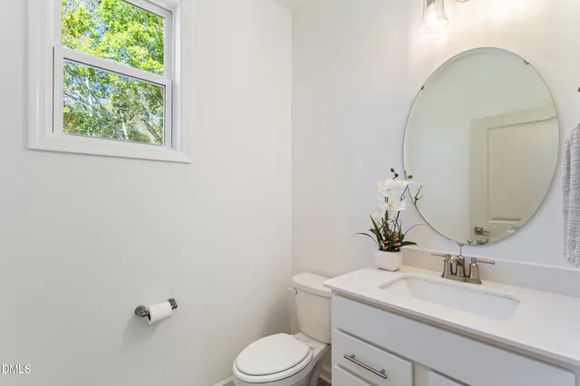 a bathroom with a toilet sink vanity and mirror