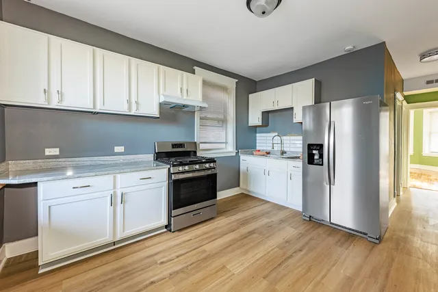 a kitchen with granite countertop a refrigerator stove top oven and sink