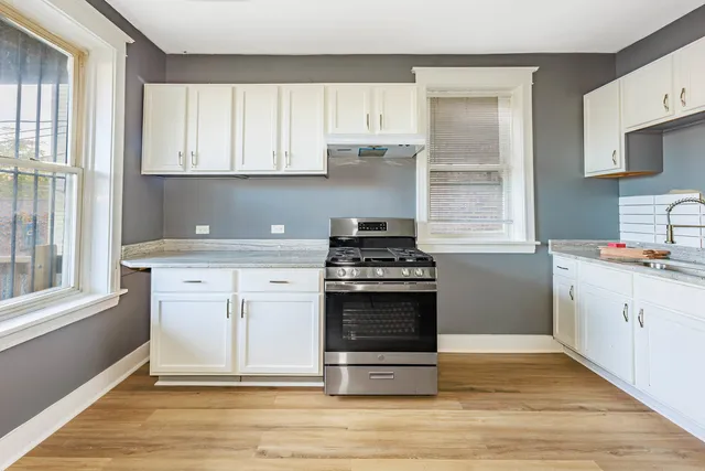 a kitchen with granite countertop a stove a sink and a window