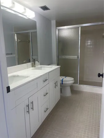 a bathroom with a double vanity sink toilet and shower