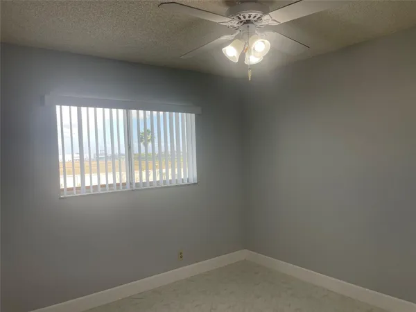 an empty room with a chandelier fan and windows