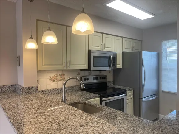 a kitchen with stainless steel appliances granite countertop a refrigerator a stove and a sink