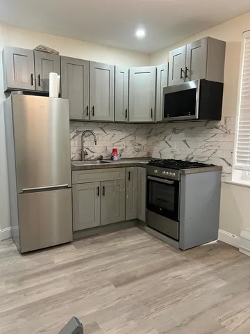 a kitchen with stainless steel appliances granite countertop a refrigerator stove a sink dishwasher and a microwave oven on the wooden floor