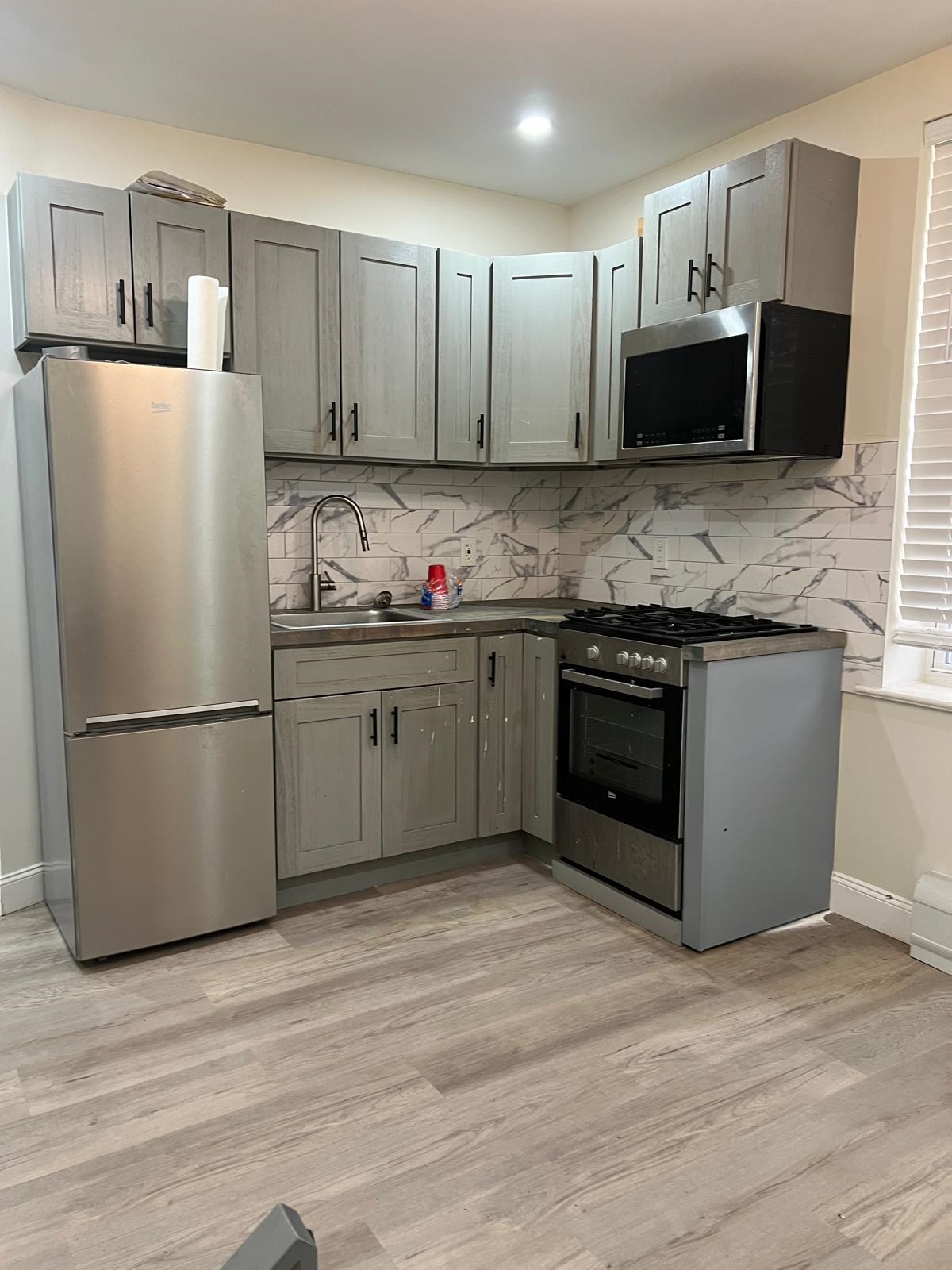 a kitchen with stainless steel appliances granite countertop a refrigerator stove a sink dishwasher and a microwave oven on the wooden floor