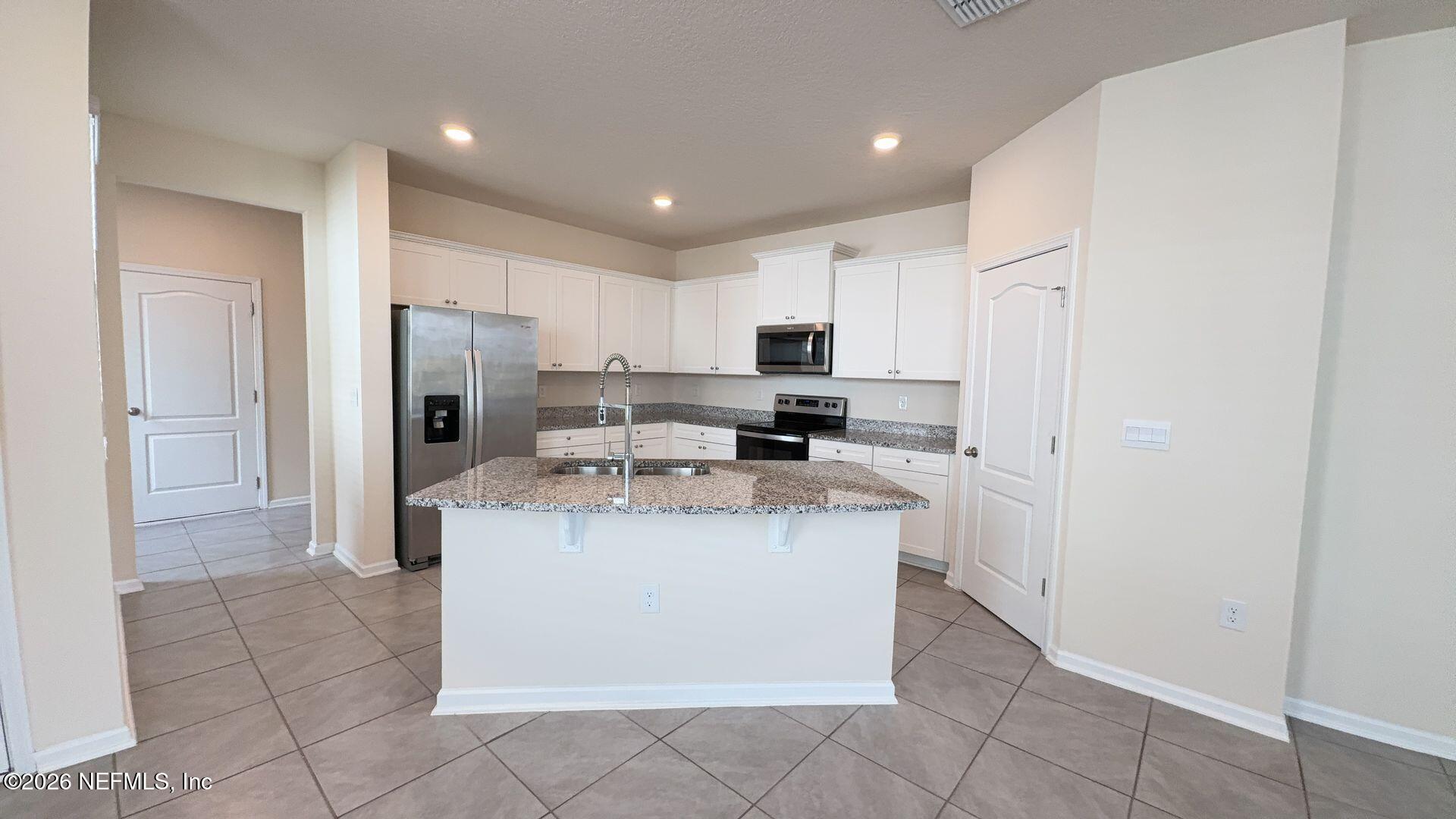 144 Redbud Road Palm Coast, FL 32137 - Photo 8 of 29 a kitchen with a refrigerator a stove top oven and a sink