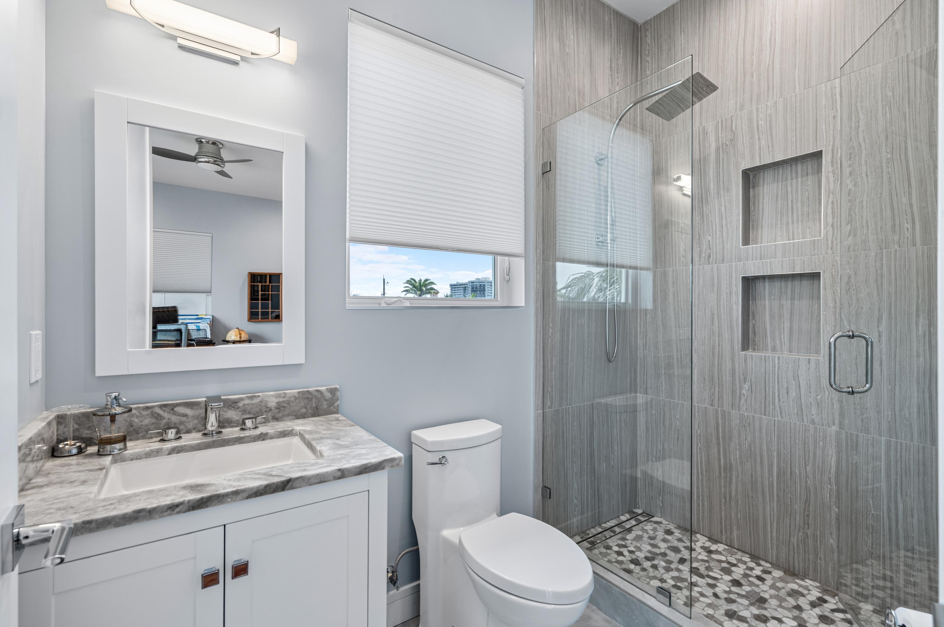 807 Dover Street Boca Raton, FL 33487 - Photo 21 of 43 a bathroom with a granite countertop sink toilet a mirror a vanity and shower