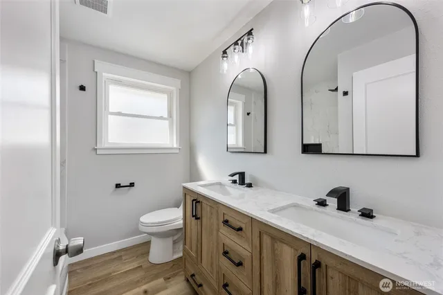 a bathroom with a double vanity sink mirror and toilet