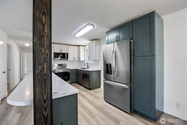 a kitchen with granite countertop stainless steel appliances a refrigerator and cabinets
