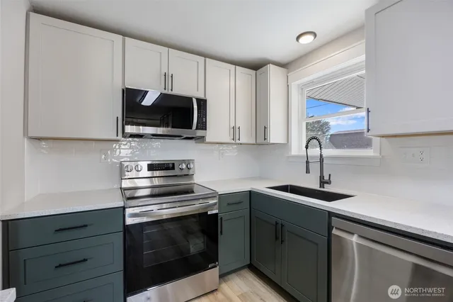 a kitchen with cabinets stainless steel appliances a sink and a microwave