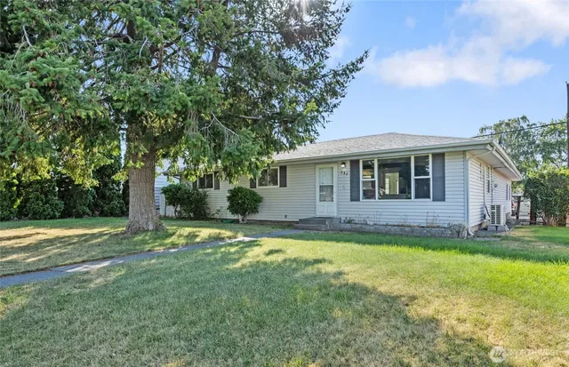 a view of a house with a big yard and large trees