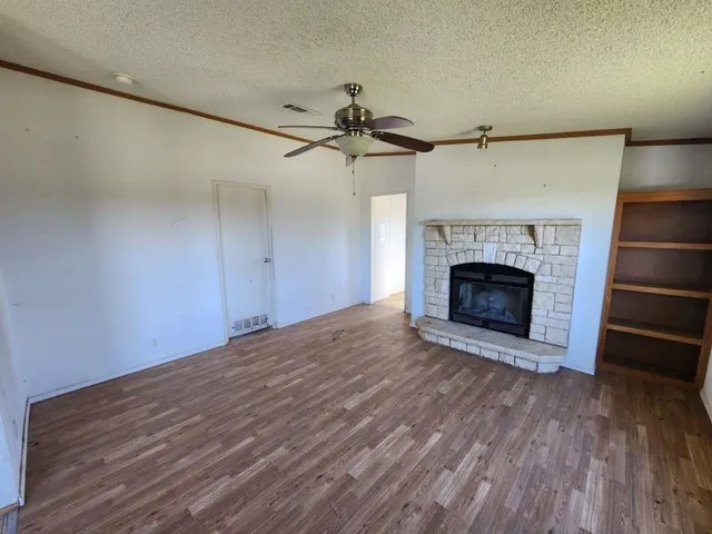a view of empty room with wooden floor fireplace and a window