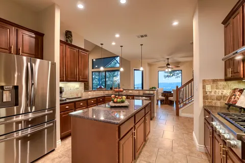 a kitchen with stainless steel appliances granite countertop a refrigerator a sink a stove and a refrigerator