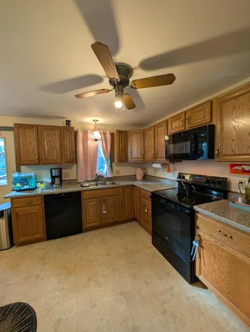 a kitchen with stainless steel appliances granite countertop a sink a stove top oven a chimney cabinets and a refrigerator