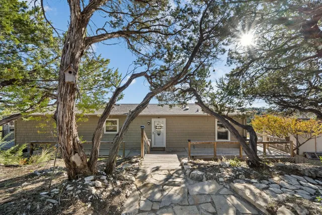 a backyard of a house with large trees and table