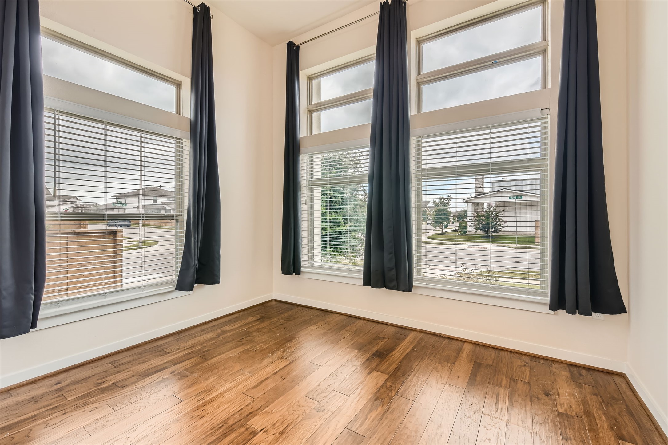 8313 Spire View Austin, TX 78744 - Photo 19 of 33 Natural light floods this versatile room through abundant windows, showcasing rich hardwood flooring.