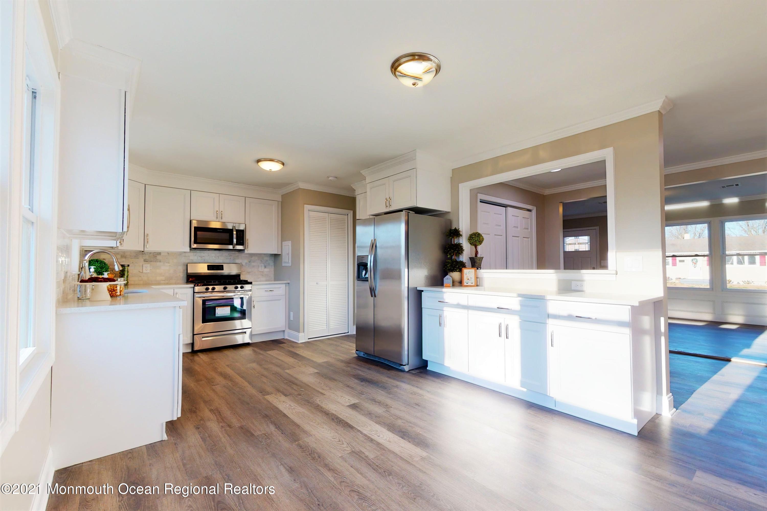 317 Stearman Road Brick, NJ 08723 - Photo 17 of 41 a kitchen with stainless steel appliances kitchen island wooden floors and white cabinets