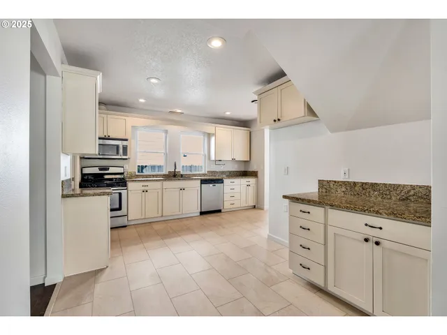 a kitchen with granite countertop white cabinets and stainless steel appliances