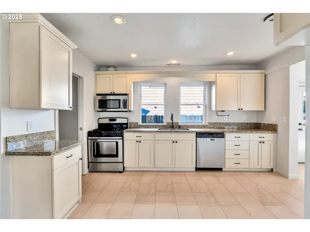 a kitchen with granite countertop white cabinets and white appliances
