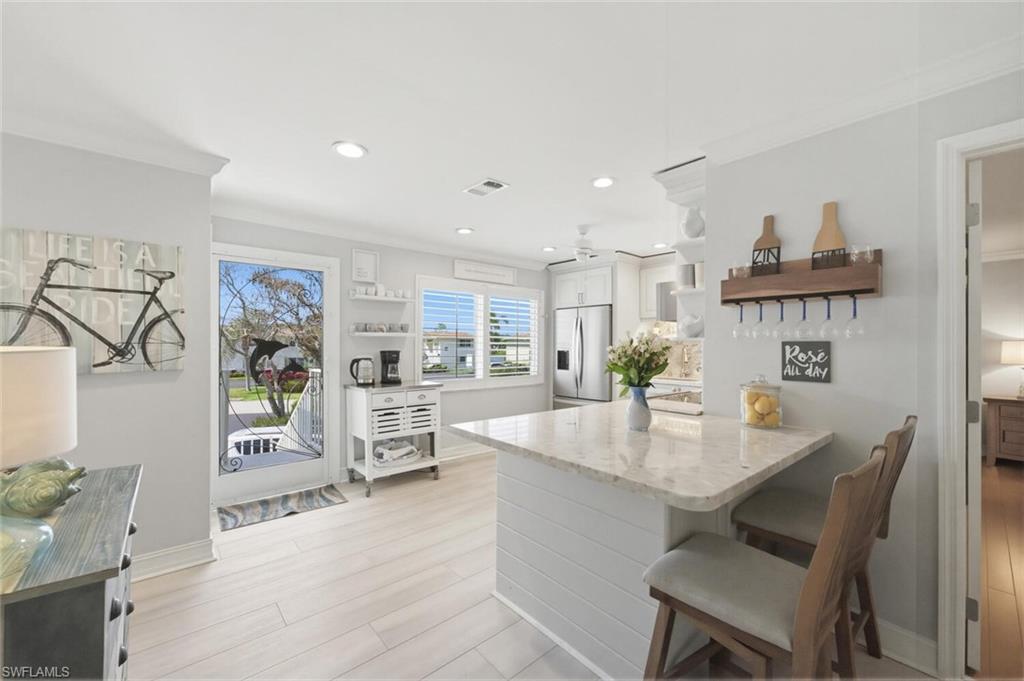 500 Teryl Road, Unit 2312 Naples, FL 34112 - Photo 1 of 46 Kitchen with a kitchen bar, open shelves, a peninsula, crown molding, and light stone counters