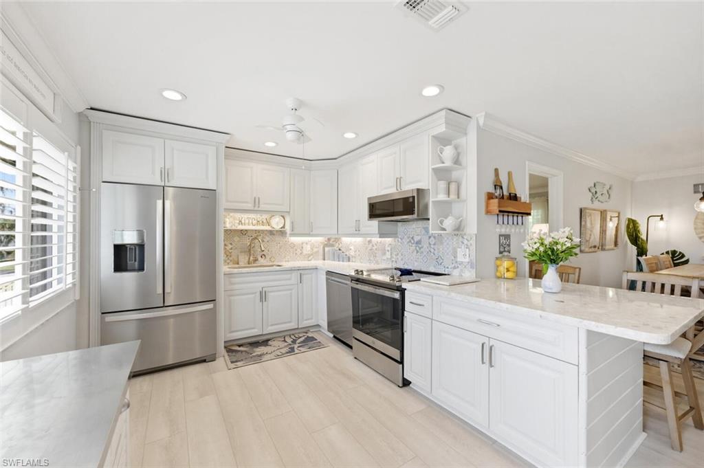 500 Teryl Road, Unit 2312 Naples, FL 34112 - Photo 2 of 46 Kitchen with stainless steel appliances, light stone countertops, crown molding, open shelves, and tasteful backsplash