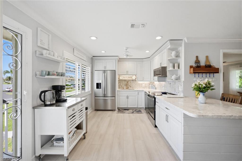 500 Teryl Road, Unit 2312 Naples, FL 34112 - Photo 3 of 46 Kitchen with open shelves, stainless steel appliances, white cabinets, backsplash, and crown molding