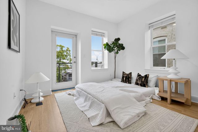 a bedroom with a bed table flowerpot and a window