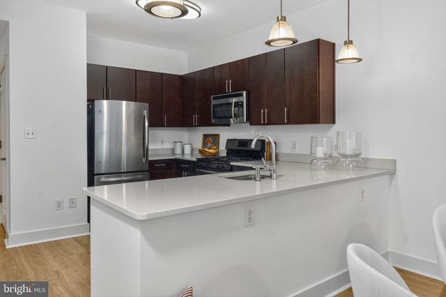 a kitchen with stainless steel appliances a refrigerator a sink a stove a microwave and wooden cabinets