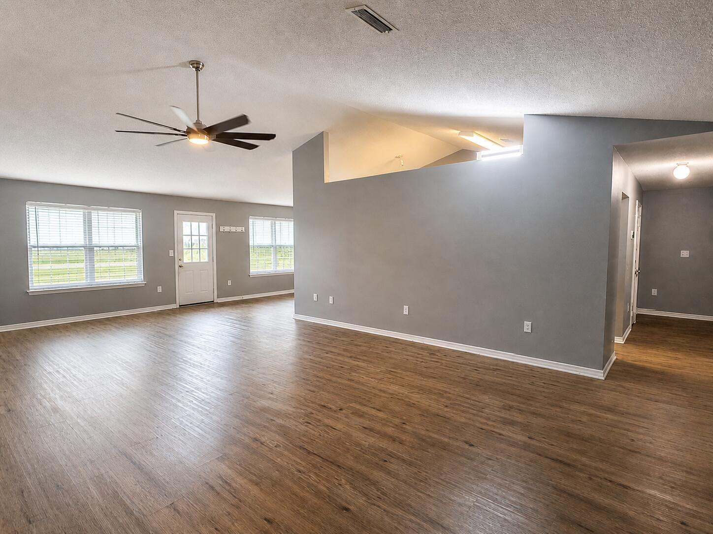 2155 Hagood Loop Crestview, FL 32536 - Photo 2 of 16 an empty room with wooden floor chandelier and windows