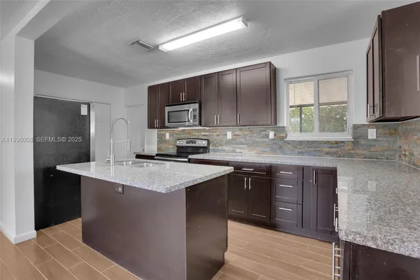 a kitchen with stainless steel appliances granite countertop a sink stove and refrigerator