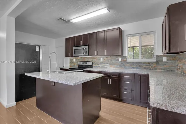 a kitchen with stainless steel appliances granite countertop a sink stove and refrigerator