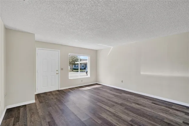 an empty room with wooden floor and window