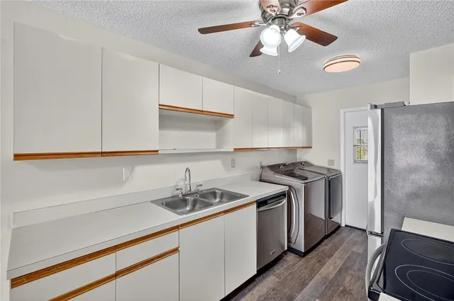 a kitchen with stainless steel appliances a refrigerator a stove a microwave oven with white cabinets