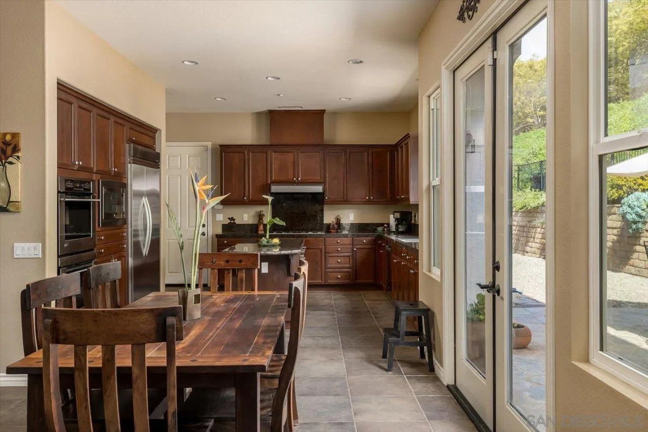 1505 Chateau Lafite Bonsall, CA 92003 - Photo 13 of 47 a kitchen with kitchen island granite countertop a refrigerator stove microwave and cabinets