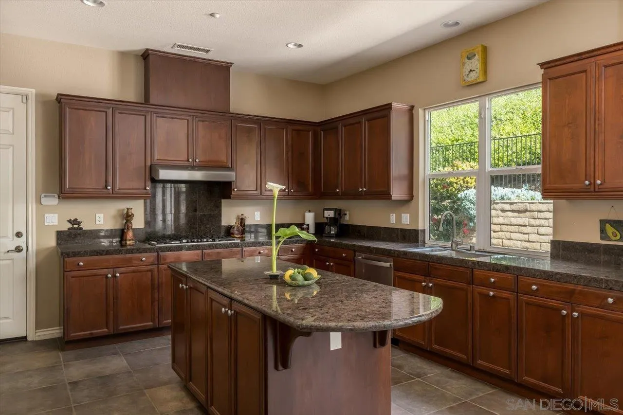 1505 Chateau Lafite Bonsall, CA 92003 - Photo 14 of 47 a kitchen with granite countertop a sink window and cabinets