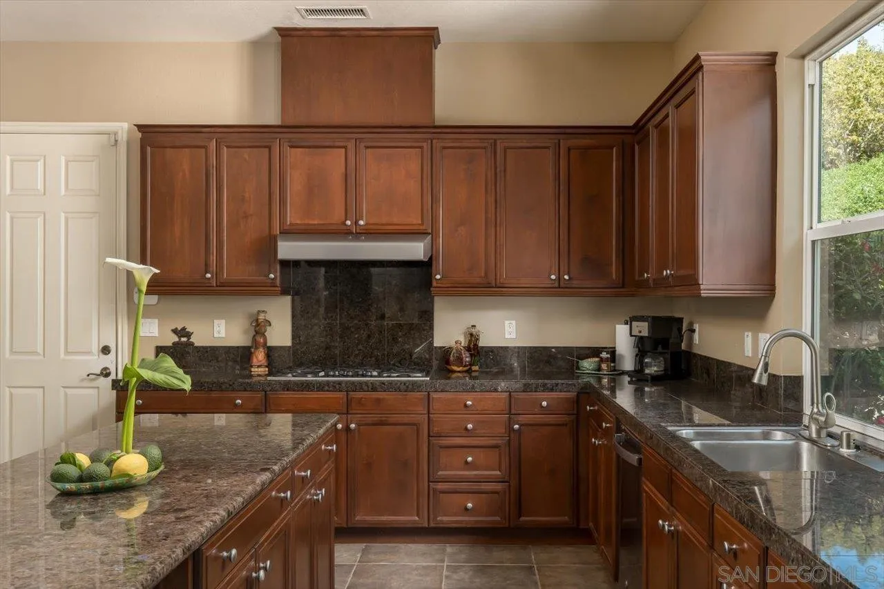 1505 Chateau Lafite Bonsall, CA 92003 - Photo 15 of 47 a kitchen with granite countertop wooden cabinets and a sink
