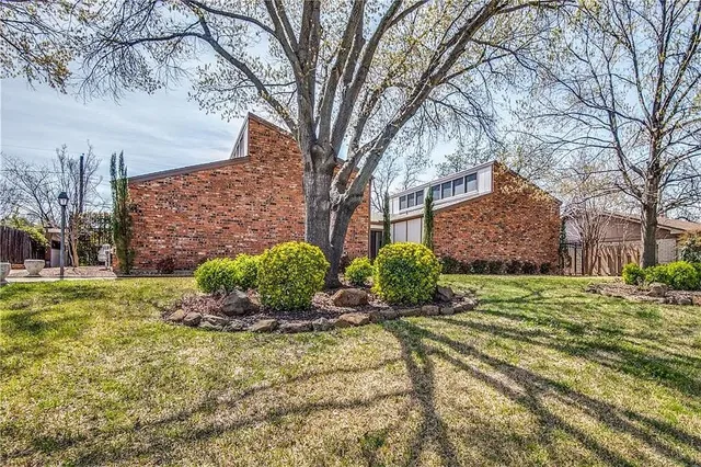 a view of a house with a large tree and a yard