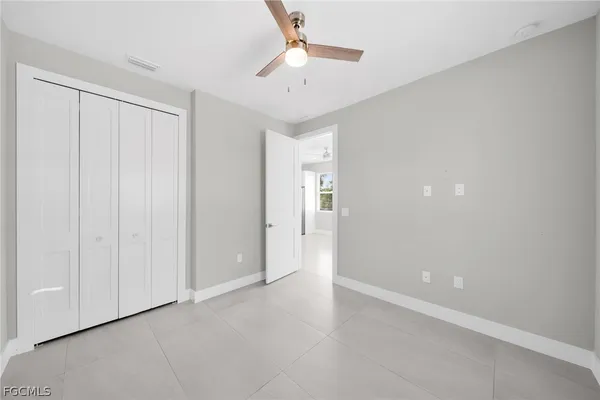 wooden floor in an empty room with a chandelier fan