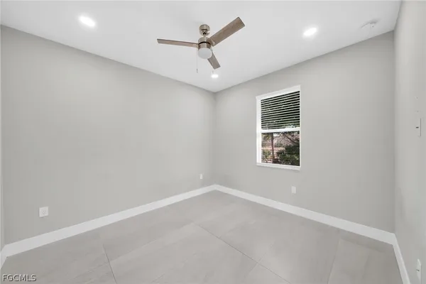 an empty room with a window and ceiling fan