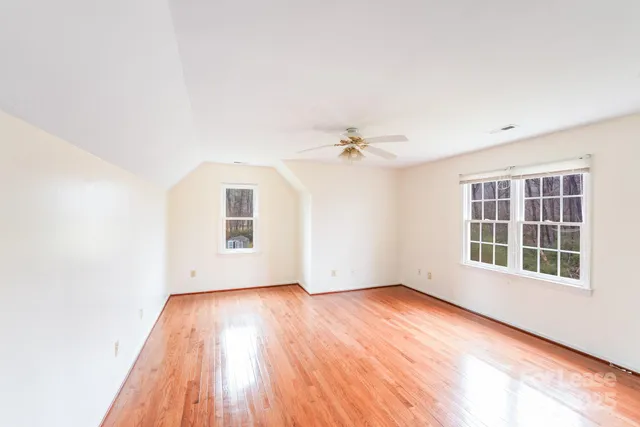 an empty room with wooden floor cabinet and windows