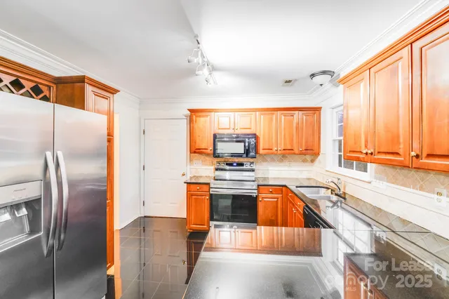 a kitchen with stainless steel appliances granite countertop a refrigerator a sink and a stove
