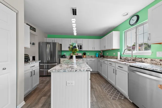 a kitchen with stainless steel appliances kitchen island granite countertop a stove refrigerator and cabinets