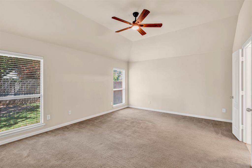 5316 Ridgeson Drive McKinney, TX 75071 - Photo 20 of 33 Vaulted ceiling with a wood-finish ceiling fan, two windows with horizontal blinds, neutral-toned carpeting, and light-colored walls