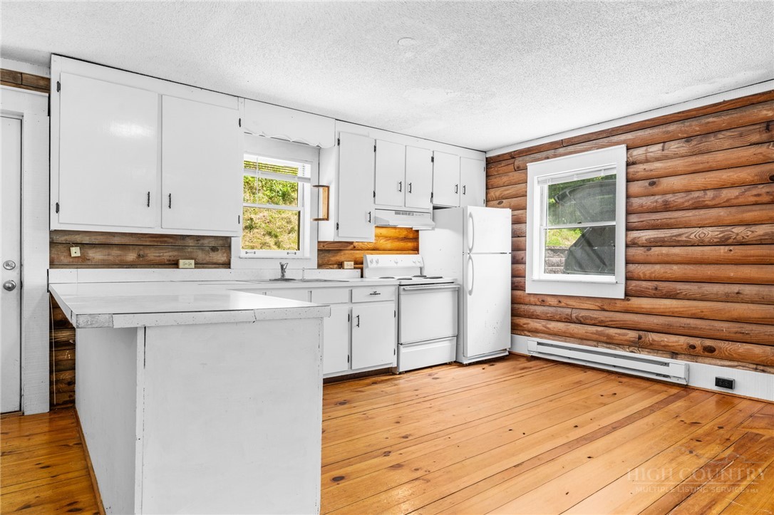233 Alpine Acres Road Vilas, NC 28692 - Photo 7 of 32 a kitchen with white cabinets and wooden floor