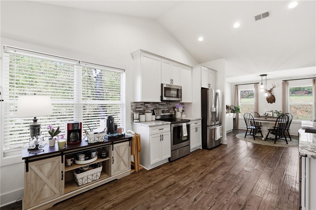 164 Mary Saphire Road Dawsonville, GA 30534 - Photo 6 of 25 a kitchen with stainless steel appliances a stove top oven a sink dishwasher a refrigerator and white cabinets with wooden floor