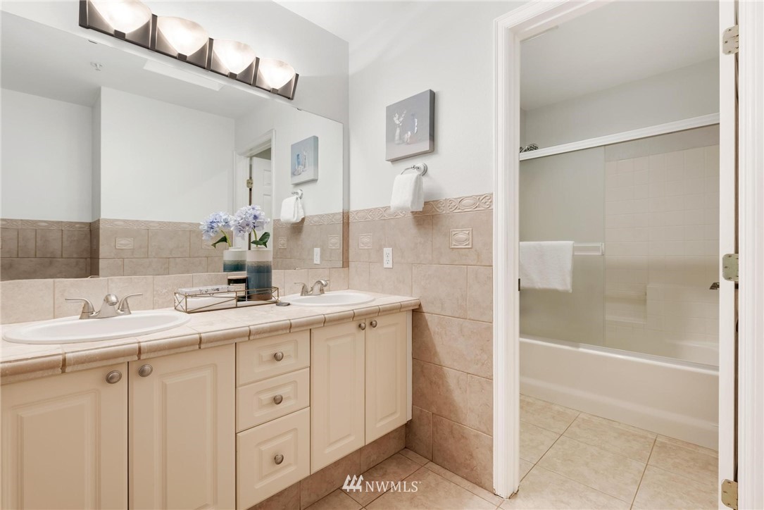 18505 Southeast Newport Way, Unit E320 Issaquah, WA 98027 - Photo 15 of 18 a bathroom with a double vanity sink mirror and shower