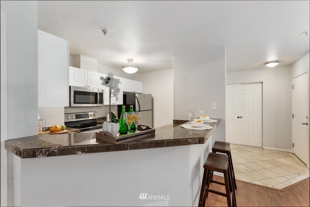 18505 Southeast Newport Way, Unit E320 Issaquah, WA 98027 - Photo 6 of 18 a kitchen with stainless steel appliances a sink a stove a microwave a refrigerator a stove with white cabinets and wooden floor
